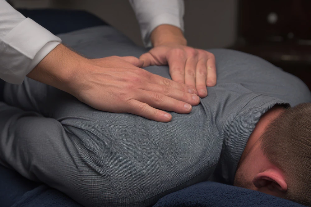 A massage therapist's hands gently press on a person's back, promoting relaxation and relief in a calm therapy setting.